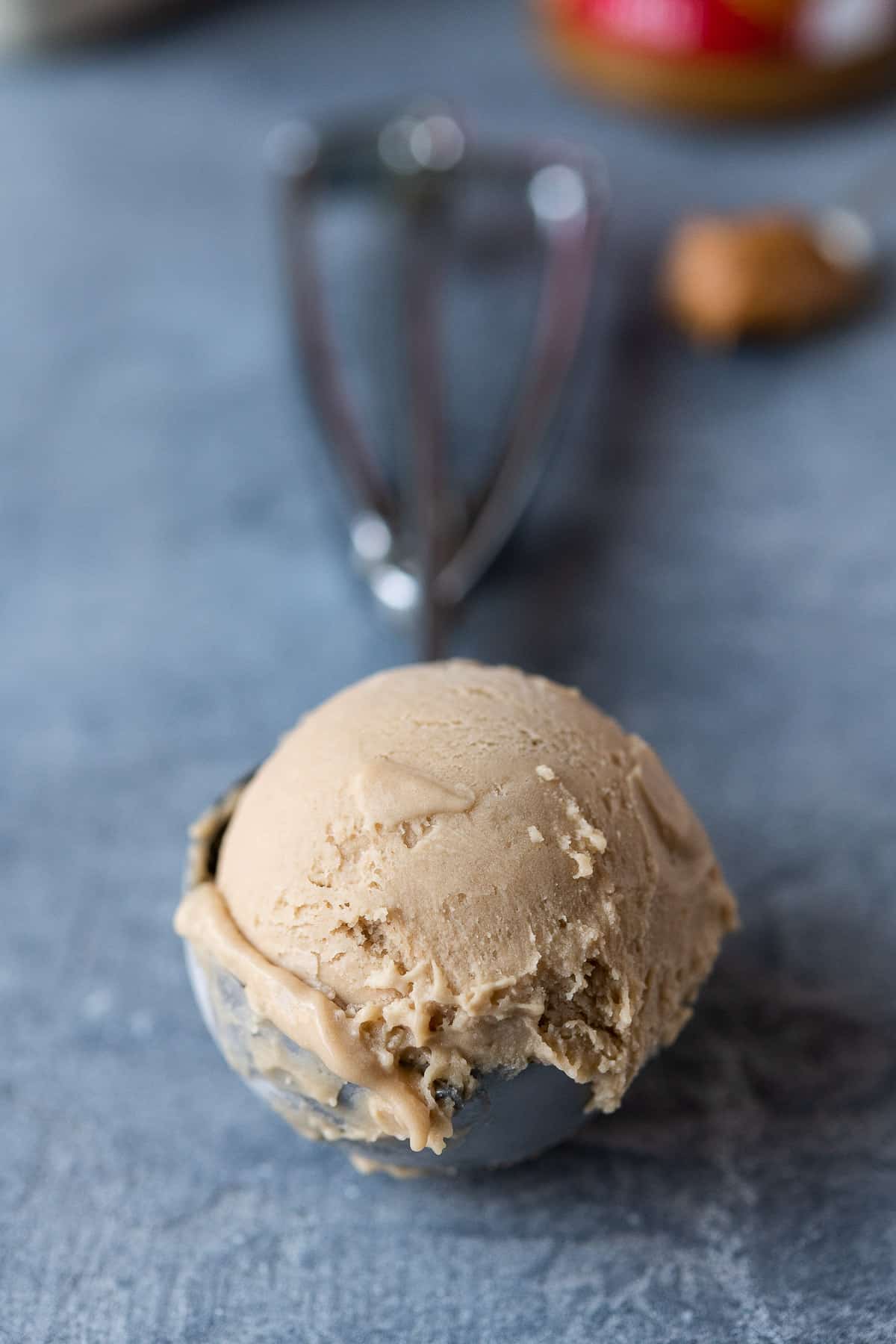 Close up of an ice cream scoop with a scoop of biscoff ice cream.